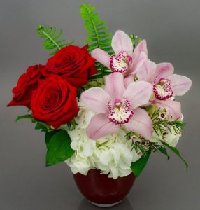 included all the favorites, like orchids, roses, and hydrangea in this design. Arranged in our imported Dutch Cosmo Vase.