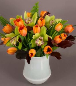 orange tuplis in vase with light green orchids